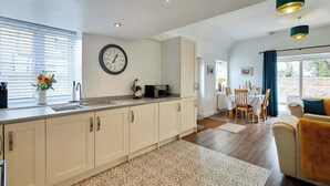 Une cuisine moderne équipée d’un évier, d’une horloge et d’un coin repas avec une table et des chaises.