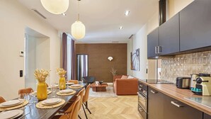 Una cocina moderna con armarios oscuros, piso de parqué de madera y un área de comedor con una mesa grande para cuatro comensales.