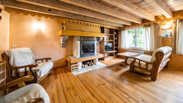 A wooden interior with a fireplace, wooden furniture, and a television.
