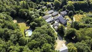 An aerial view of a residential area with multiple houses, a swimming pool, and surrounding greenery.