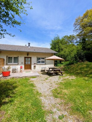 A house with a patio, a table, and chairs. - Cool Forest Retreat with Pool (Le Soulié)