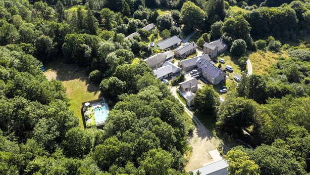 An aerial view of a residential area with multiple houses, a swimming pool, and surrounding greenery. - Cool Nature Retreat with Pool in the Heart of the Forest (Le Soulié)