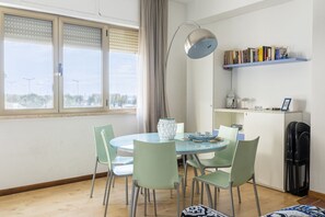 A dining area with a round table, green chairs, a vase, and a lamp. - GuestHost - Bagni Pancaldi Modern Studio (Livorno)