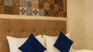A bed with a headboard, two pillows, and a blue accent pillow. - Rosewood By Zenvana (Dehradun)