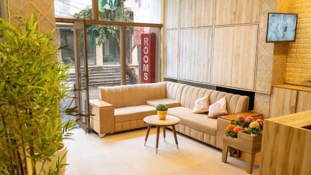 A modern hotel lobby with a sofa, a small round table, a potted plant, and a wooden bench with flowers. - Rosewood By Zenvana (Dehradun)
