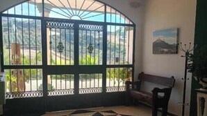 Una habitación con un amplio ventanal arqueado, piso a cuadros, un banco y un cuadro en la pared.