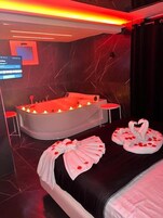 Un spa moderno con una bañera grande, dos mesitas auxiliares y toallas decorativas con forma de cisne.