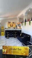 Zona de recepción de hotel con suelo de mármol, un mostrador de recepción, un sofá y una zona de bar con estantes llenos de botellas.