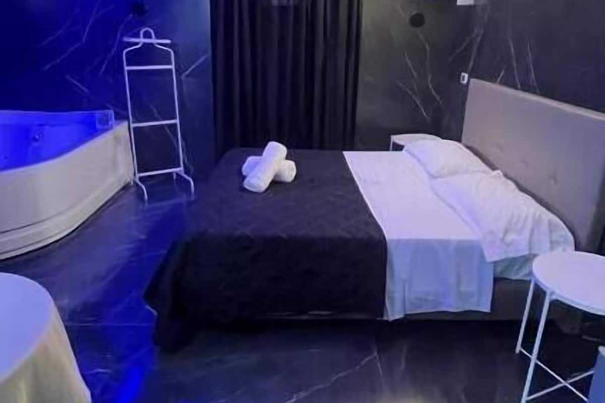 Una habitación de hotel moderna con una cama, una mesita, una silla y un banco curvo.