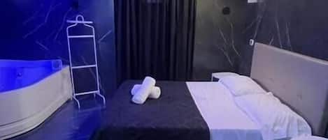 Une chambre d’hôtel moderne comprenant un lit, une petite table, une chaise et un banc incurvé.