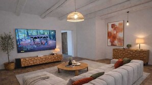 A living room with a large flat-screen TV, a sofa, a coffee table, and a decorative console. - Mas en Provence (Eyguières)