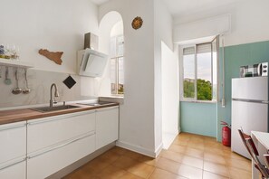 Eine Küche mit weißen Schränken, einer Holz Arbeitsplatte, einem Spülbecken und einem Fenster mit Blick auf Grünflächen.