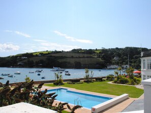 Ein Pool mit Blick auf Boote auf dem Wasser und Hügel im Hintergrund.