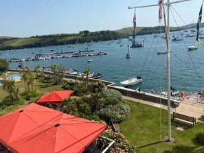 Ein Yachthafen mit Booten, einer Fahnenmast und einem roten Sonnenschirm.
