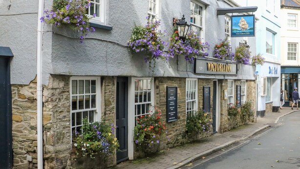 A Victorian Inn with stone walls, hanging flower baskets, and a signboard listing amenities. - 24 The Salcombe (Salcombe)