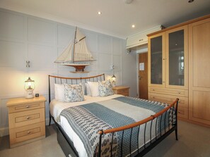 Ein Schlafzimmer mit einem Bett, Nachttischen, einem Holzschrank und einer Segelboot-Dekoration.