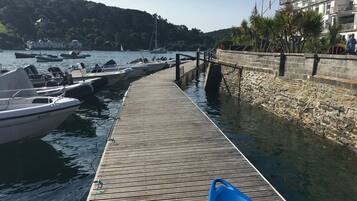 Un muelle de madera que lleva a un puerto deportivo con barcos amarrados a la izquierda.