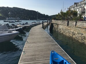 Un muelle de madera que lleva a un puerto deportivo con barcos amarrados a la izquierda.