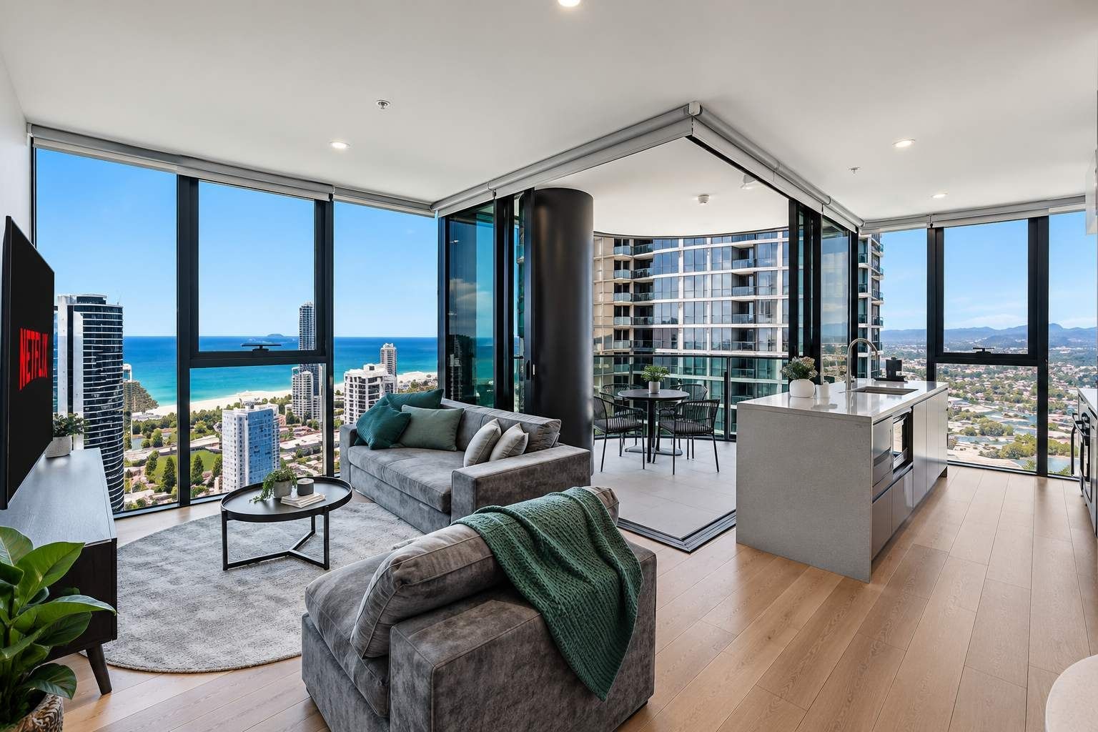 A modern living room with a large window overlooking a cityscape and beach.