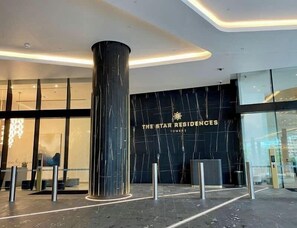 A modern hotel entrance with a prominent black marble pillar and glass doors. - Lvl 36 at The Star | 2BR Ocean View, Pool, Parking (Broadbeach)