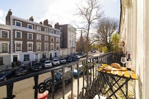 A balcony with a table, a bottle, and a glass. - The Primrose Princesa with A/C - by Out of Office Lifestyle (Greater London)