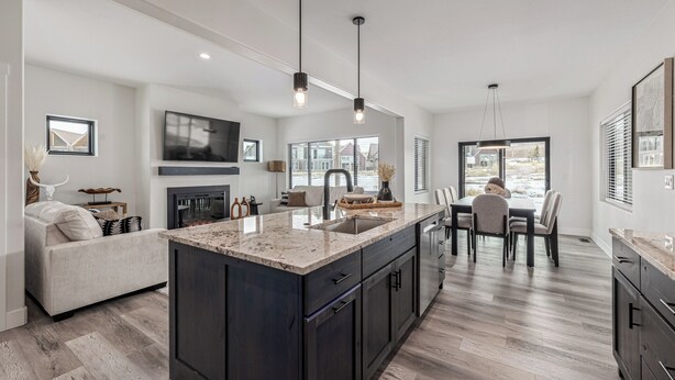 A modern kitchen with a large island, dark cabinetry, and pendant lighting.