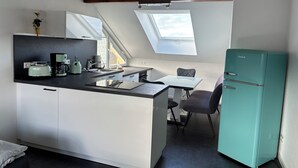 Una cocina compacta con comedor, un refrigerador verde azulado y tragaluces.