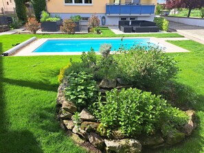 A swimming pool surrounded by a well-maintained lawn and a rock garden.