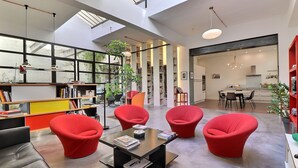 Ein geräumiges Zimmer mit hoher Decke, großen Fenstern und modernem Design.