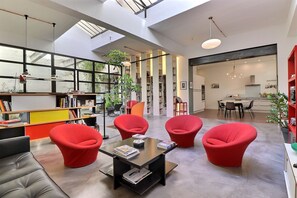 Ein geräumiges Zimmer mit hoher Decke, großen Fenstern und modernem Design.