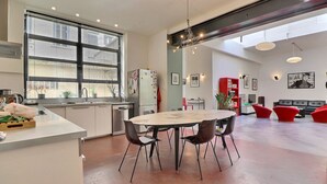 Eine moderne Küche mit Essbereich, großen Fenstern und einem roten Sofa in einem geräumigen Wohnzimmer.
