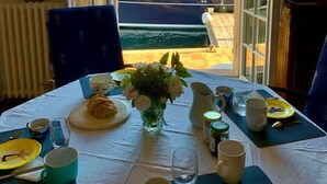 Una mesa de comedor con vistas a barcos y edificios a través de puertas abiertas.