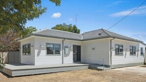 A single-story mobile home with a flat roof, a front porch, and a small front yard.