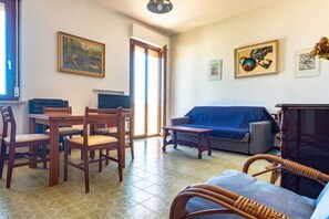 Ein Wohnzimmer mit Esstisch, Stühlen, einer Couch, einem Fernseher und Kunstwerken an den Wänden.
