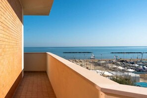 Ein Balkon mit Meerblick, ein Parkplatz und ein Gebäude mit Backsteinfassade.