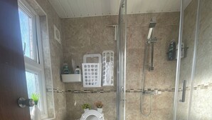 Un baño con inodoro, ducha y cabina de ducha con paredes de vidrio.