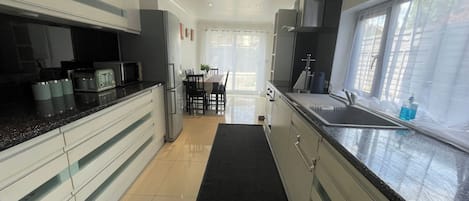A modern kitchen with a black countertop, stainless steel appliances, and a dining area with a table and chairs.