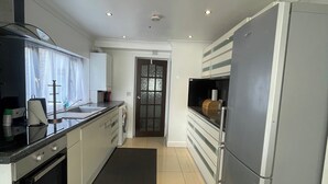 Una cocina moderna con un refrigerador de acero inoxidable, horno empotrado y encimera negra.