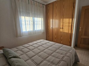 Ein Schlafzimmer mit einem Bett, einem Kleiderschrank und einem Fenster mit Vorhängen.