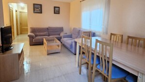 A living room with a sofa, a coffee table, a TV, and a dining table with chairs. - Central house with private pool - 4 guests (Mont-roig del Camp)