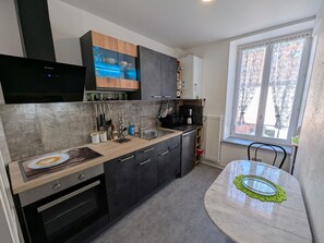 Una cocina moderna con horno empotrado, cafetera y comedor con mesa y sillas.