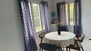 Ein Essbereich mit einem runden Tisch, Stühlen und einer Vase mit Blumen.