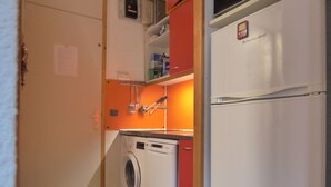 Une cuisine compacte équipée d’un lave-linge, d’un réfrigérateur et d’un four à micro-ondes.