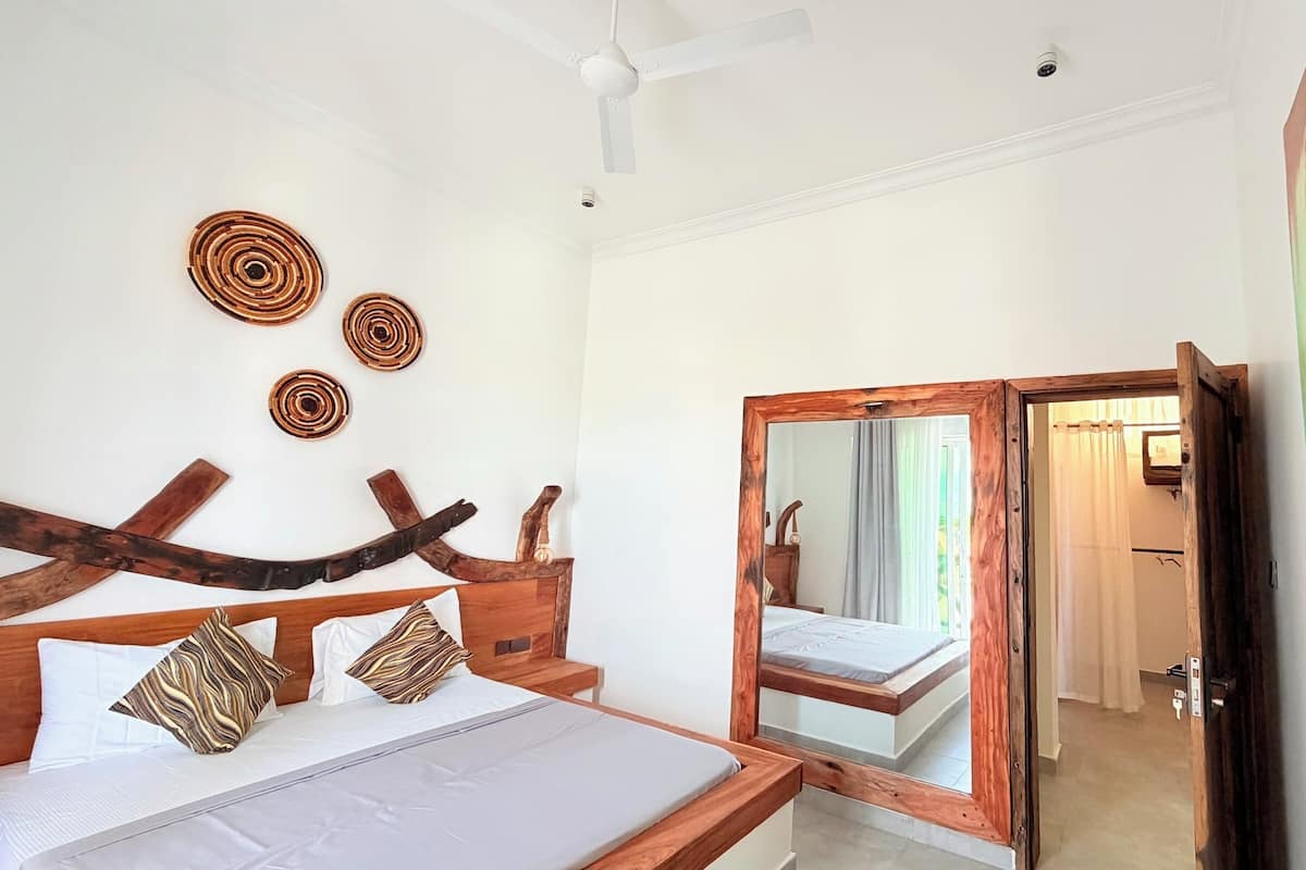 A bedroom with a wooden bed, a mirror, and a painting on the wall.