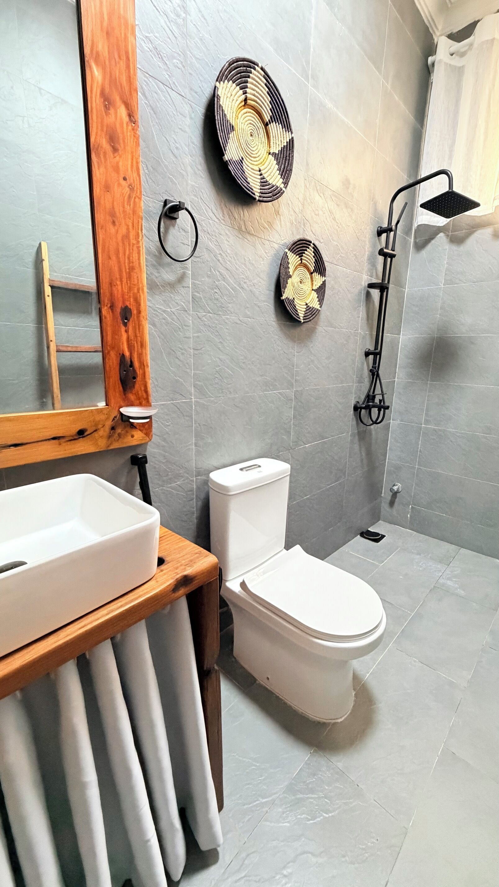 Et badeværelse med en trævask, toilet i hvidt og en bruseniche.