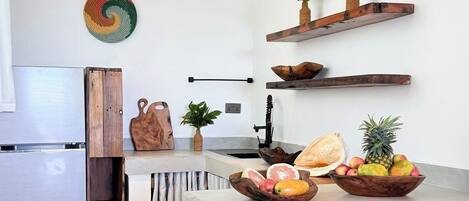 A modern kitchen with a central island, wooden stools, and decorative plates on the wall.