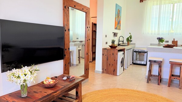 A modern kitchen with a built-in oven, a sink, and a dining area with a wooden table and chairs.
