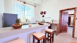 Une cuisine moderne dotée d’un îlot central, de tabourets de bar, d’une grande fenêtre et d’œuvres d’art décoratives sur les murs.