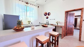 A modern kitchen with a central island, bar stools, a large window, and decorative wall art.