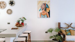 Une cuisine moderne avec un coin bar, une table à manger avec des tabourets et un tableau accroché au mur.